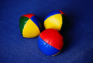 Three juggling balls in front of a blue  background