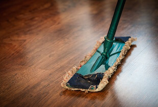 A broom sweeping across a wooden floor.