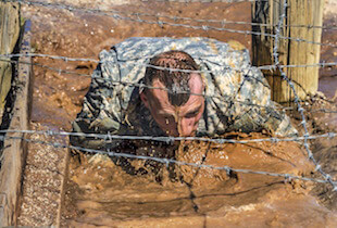 A soldier going under barbed wire.