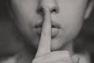 A woman holding a finger over her mouth, epitomizing the secrets of successful bloggers.