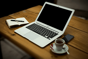 A laptop next to a cup of coffee.
