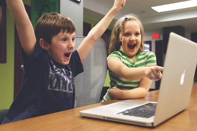 Two happy kids looking at a laptop.