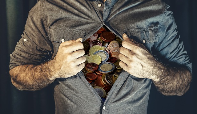 A man opening his shirt to reveal a stack of coins.